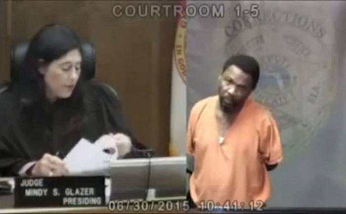 Booth enters the courtroom before Judge Glazer.