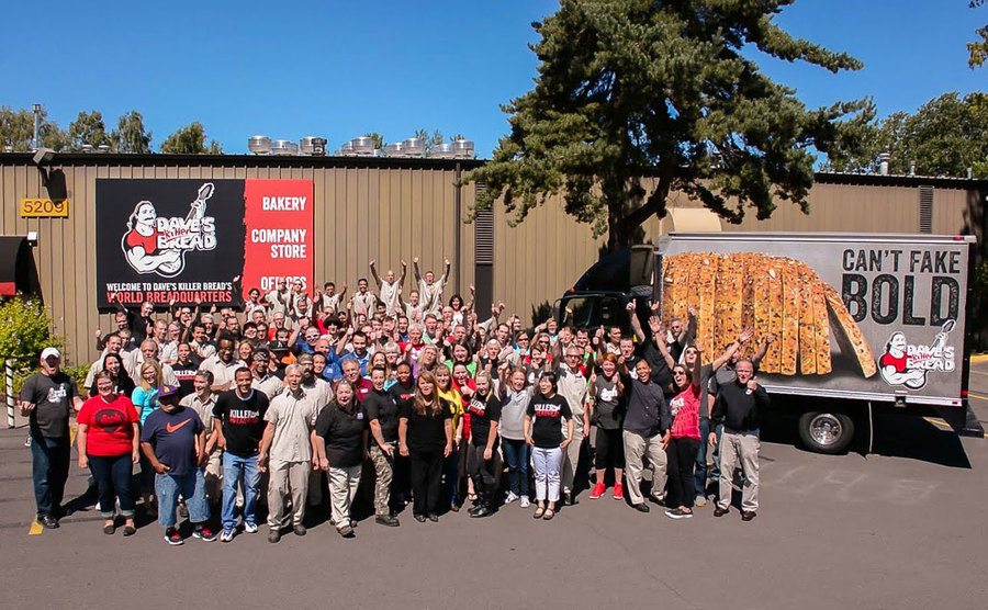 A large group of employees pose outside Dave’s Killer Bread.