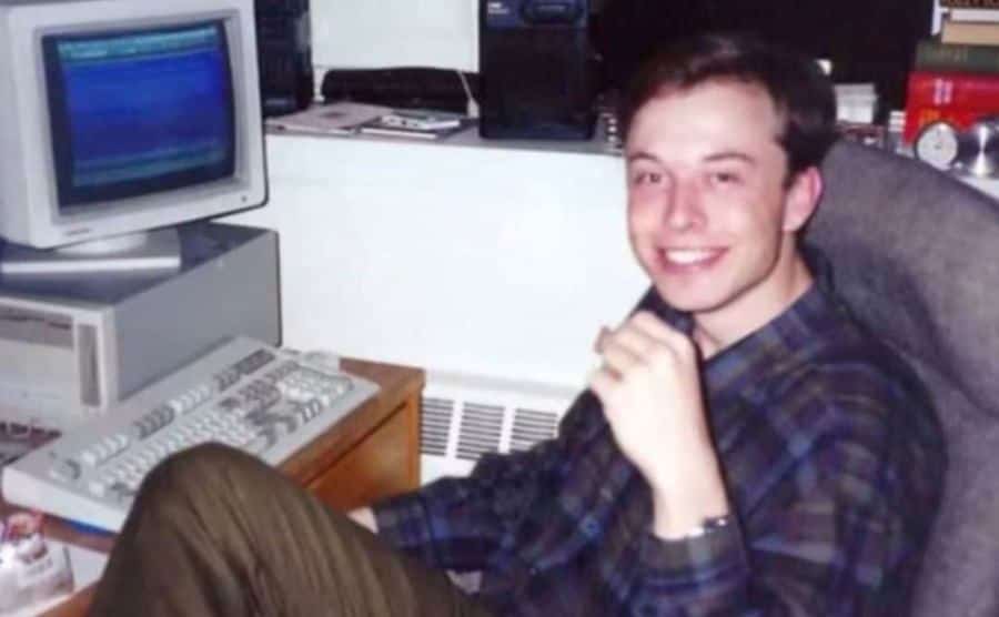 A photo of Musk as a teenager sitting in front of a computer.