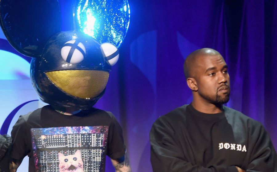 Deadmau5 and Kanye West stand on stage.