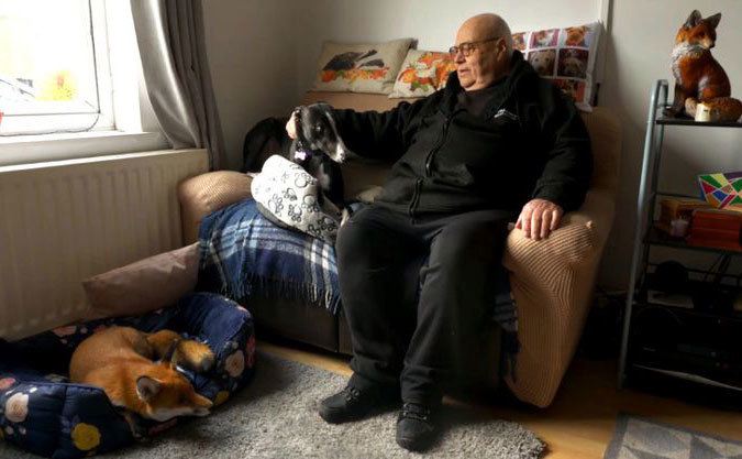 Geoff Grewcock sits with his dog at home.