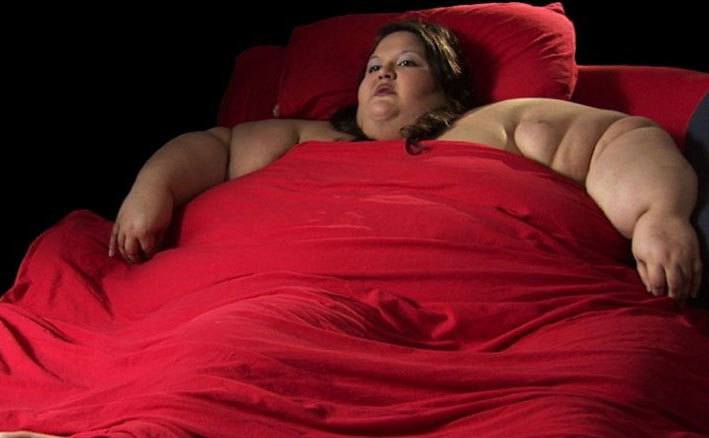 An over-weight woman is lying in bed.