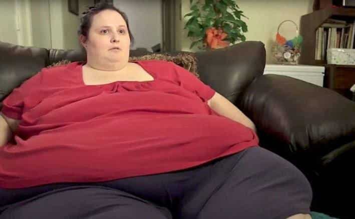 An overweight woman is sitting at home.