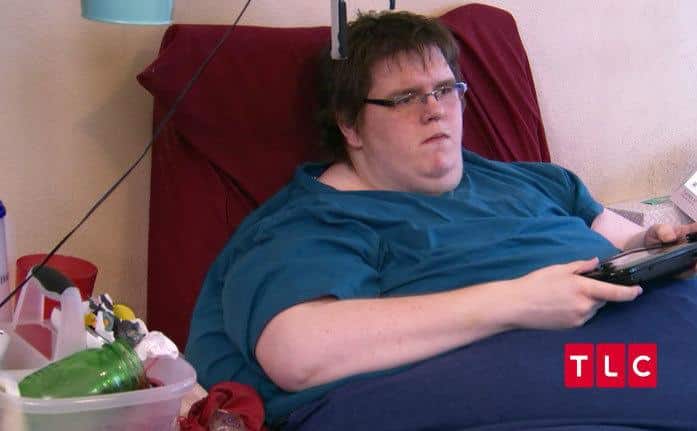 Sean Milliken is playing video games in bed.