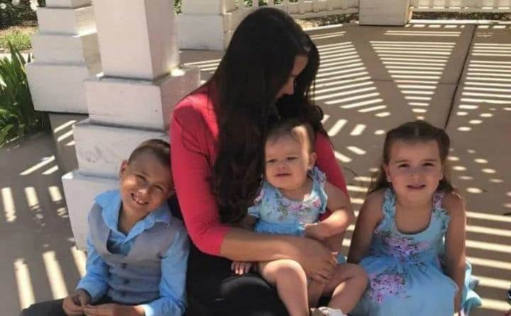 Natasha sits in a park with her kids.