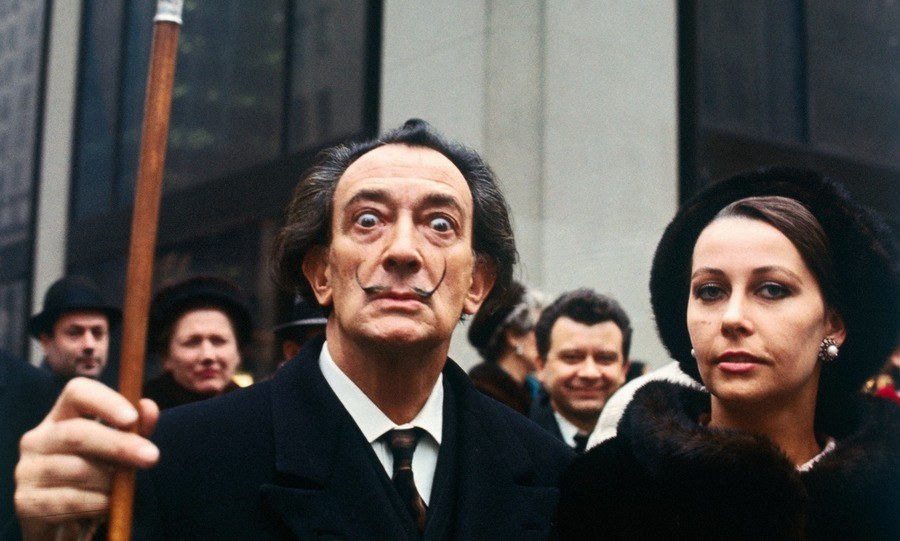 Artist Salvador Dali, lifting his cane, with a woman in New York.