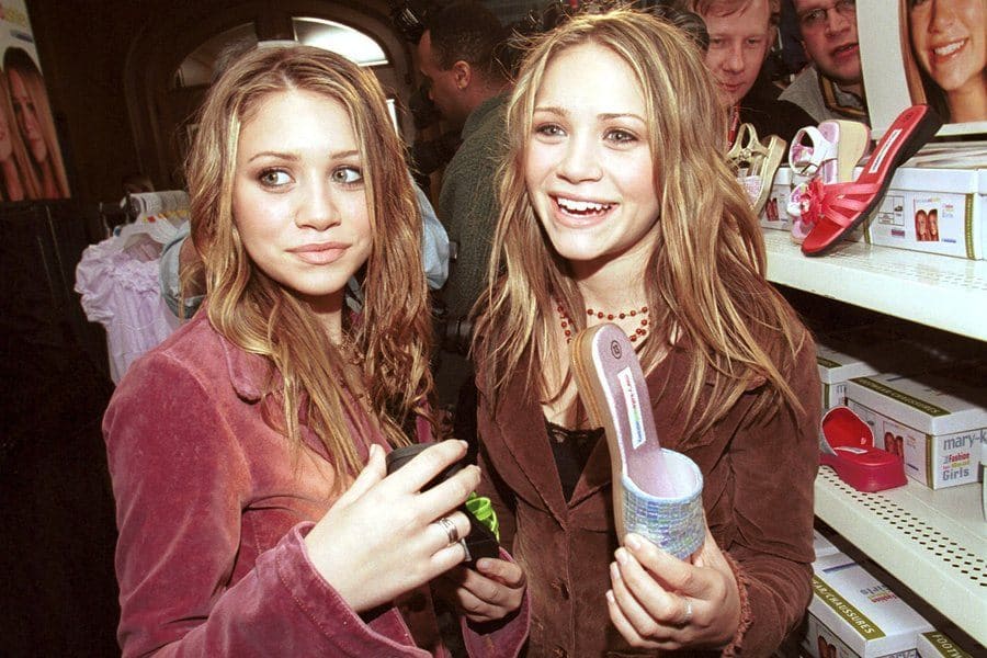 Mary-Kate and Ashley Olsen were announcing their partnership with Walmart while holding a shoe from their line of clothing.