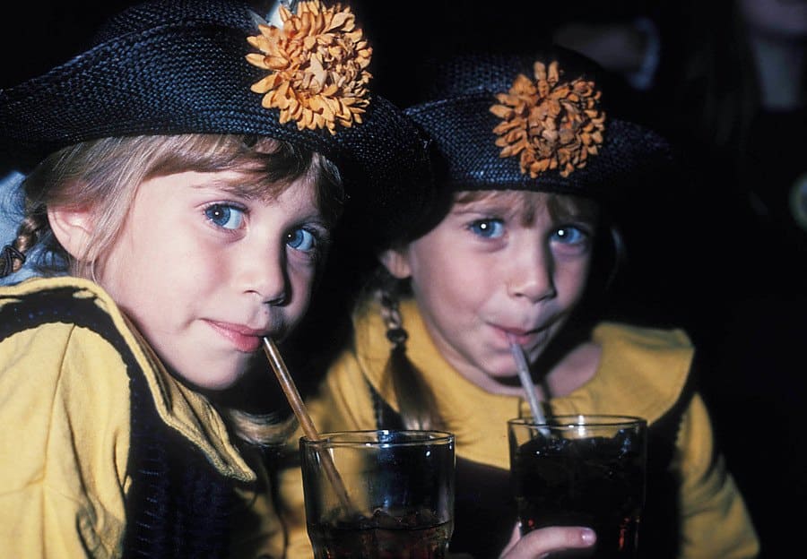Mary-Kate and Ashley Olsen in 1992 wth sunflower hats and yellow shirts on.