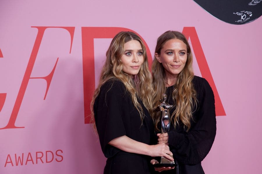 Mary-Kate and Ashley Olsen at the Fashion Awards on the winners walk holding their award in 2019.