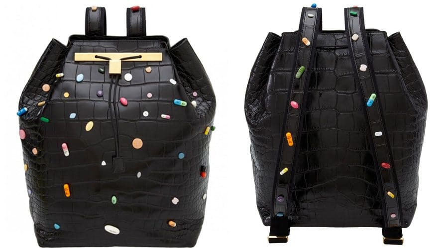 A black leather bag with gold accents and pills all over the outside of the bag.